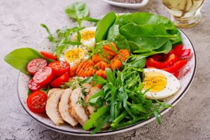 plate-with-keto-diet-food-cherry-tomatoes-chicken-breast-eggs-carrot-salad-with-arugula-spinach-keto-lunch-min
