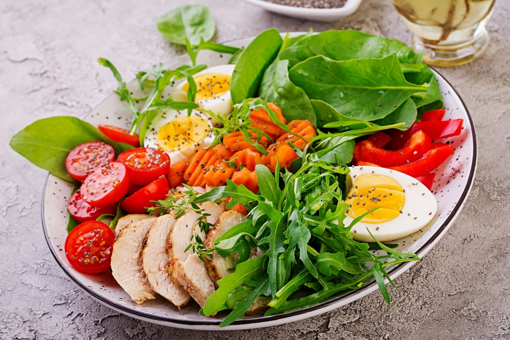 plate-with-keto-diet-food-cherry-tomatoes-chicken-breast-eggs-carrot-salad-with-arugula-spinach-keto-lunch-min